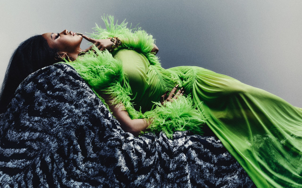 Cardi B in a green dress on a grey chair