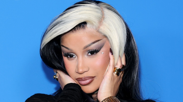 Cardi B attends an event in a sheer dress. Her hair is equal parts dark and light and she wears cateye liner.